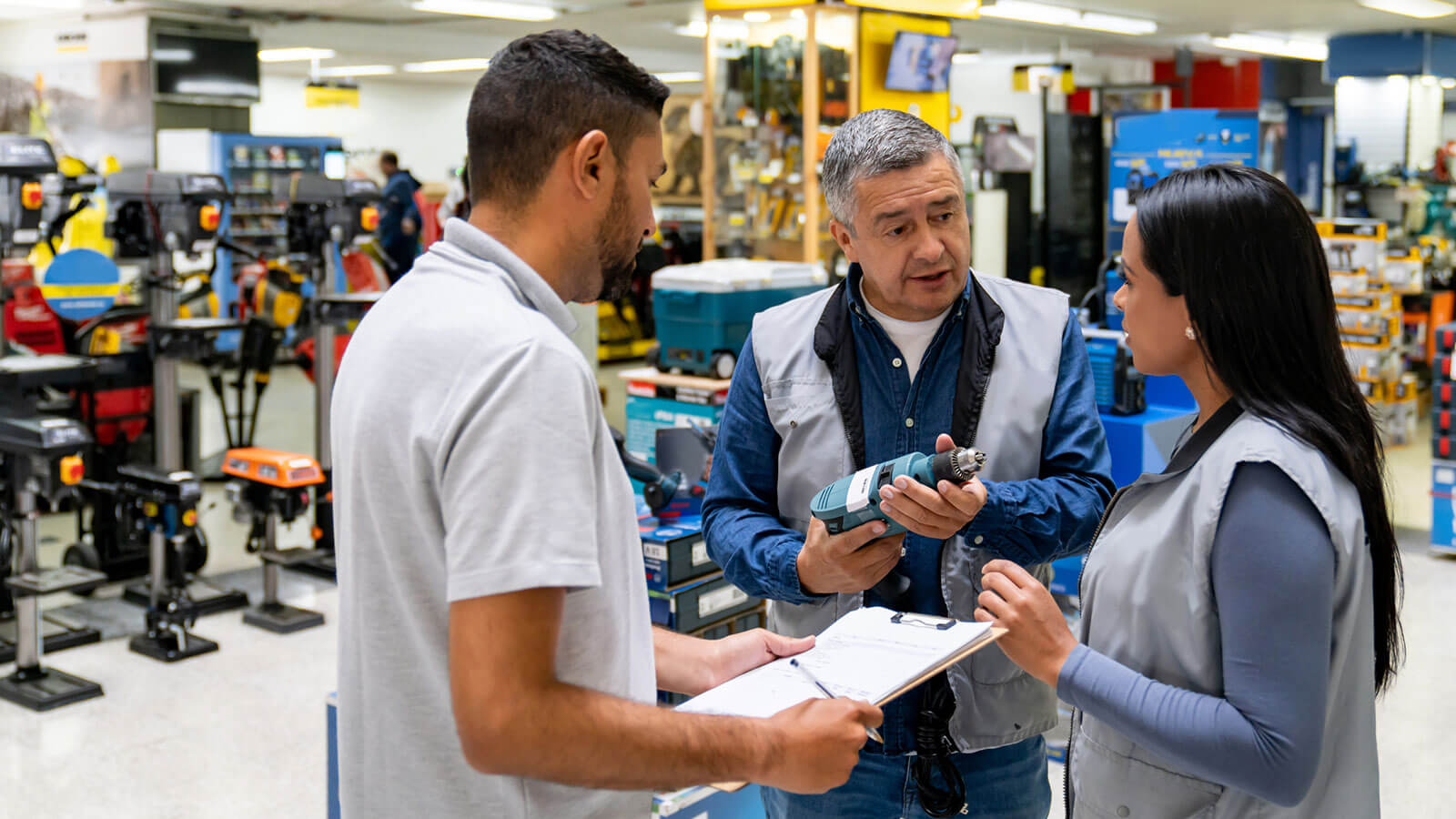 A small business owner talks with his key employees about available inventory in his hardware store.