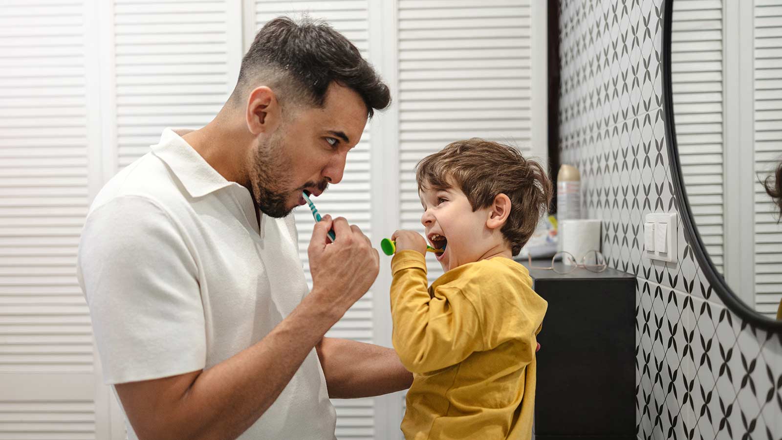 Father and son brushing their teeth in the bathroom.