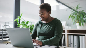 A woman reviews her employer-sponsored retirement plan on her laptop and reviews simple steps she can take to help boost her plan.