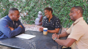 Three people gathered around a table, having a discussion and laughing.