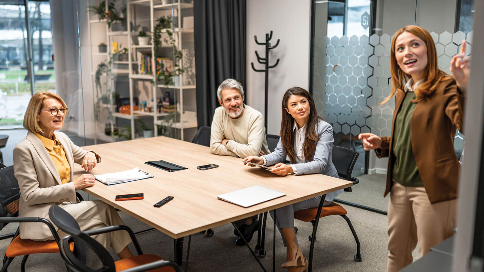 A group of employees collaborate in a modern office conference room, working on a whiteboard, discussing an upcoming project.