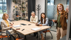 A group of employees collaborate in a modern office conference room, working on a whiteboard, discussing an upcoming project.