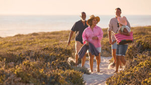 Two couples in their late 50s are on vacation, laughing as they leave the beach after a fun day.