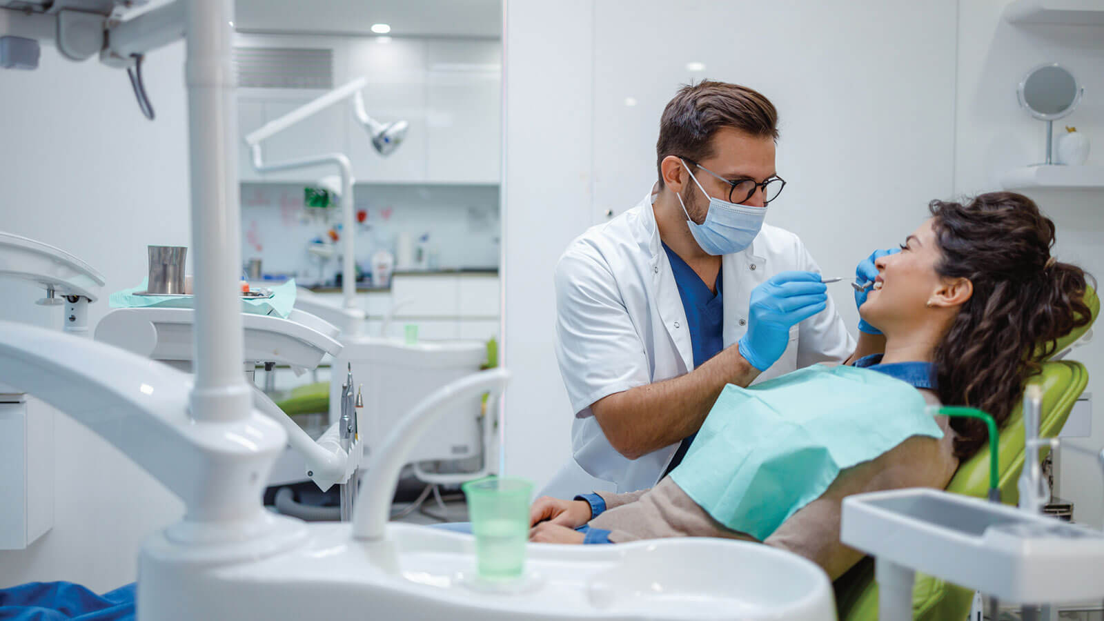 Dentist working on smiling patient in dental chair.