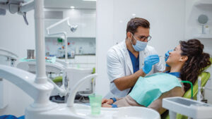 Dentist working on smiling patient in dental chair.