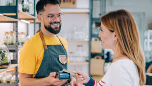 A business owner assists a customer at checkout, reflecting the business planning and protection needs discussed in term life insurance strategies.
