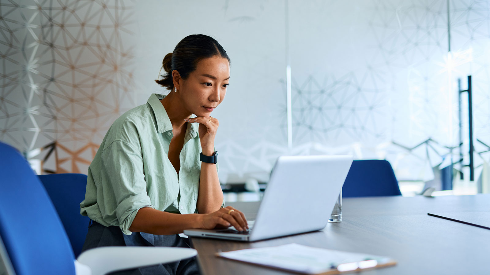  An employee reviews retirement savings tips on her laptop at a desk in her workplace.