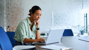  An employee reviews retirement savings tips on her laptop at a desk in her workplace.