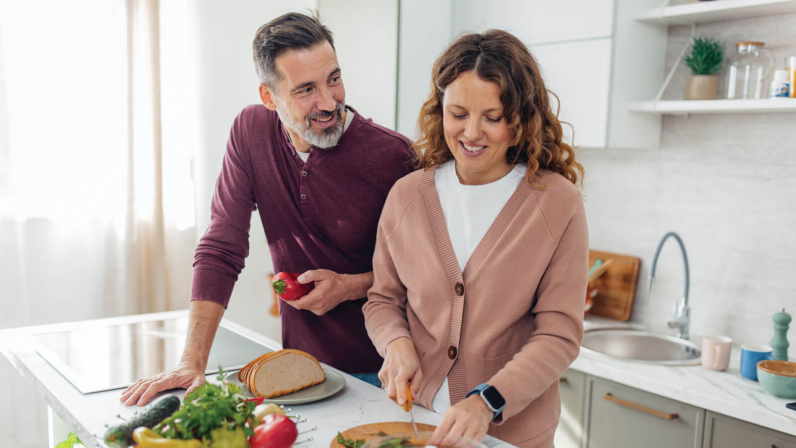 A husband and wife prepare dinner together in their kitchen at home.