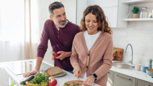 A husband and wife prepare dinner together in their kitchen at home.