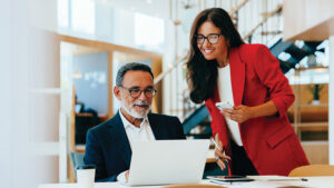 A business owner and next-generation family member discuss long-term business continuity and wealth transfer plans in their office.