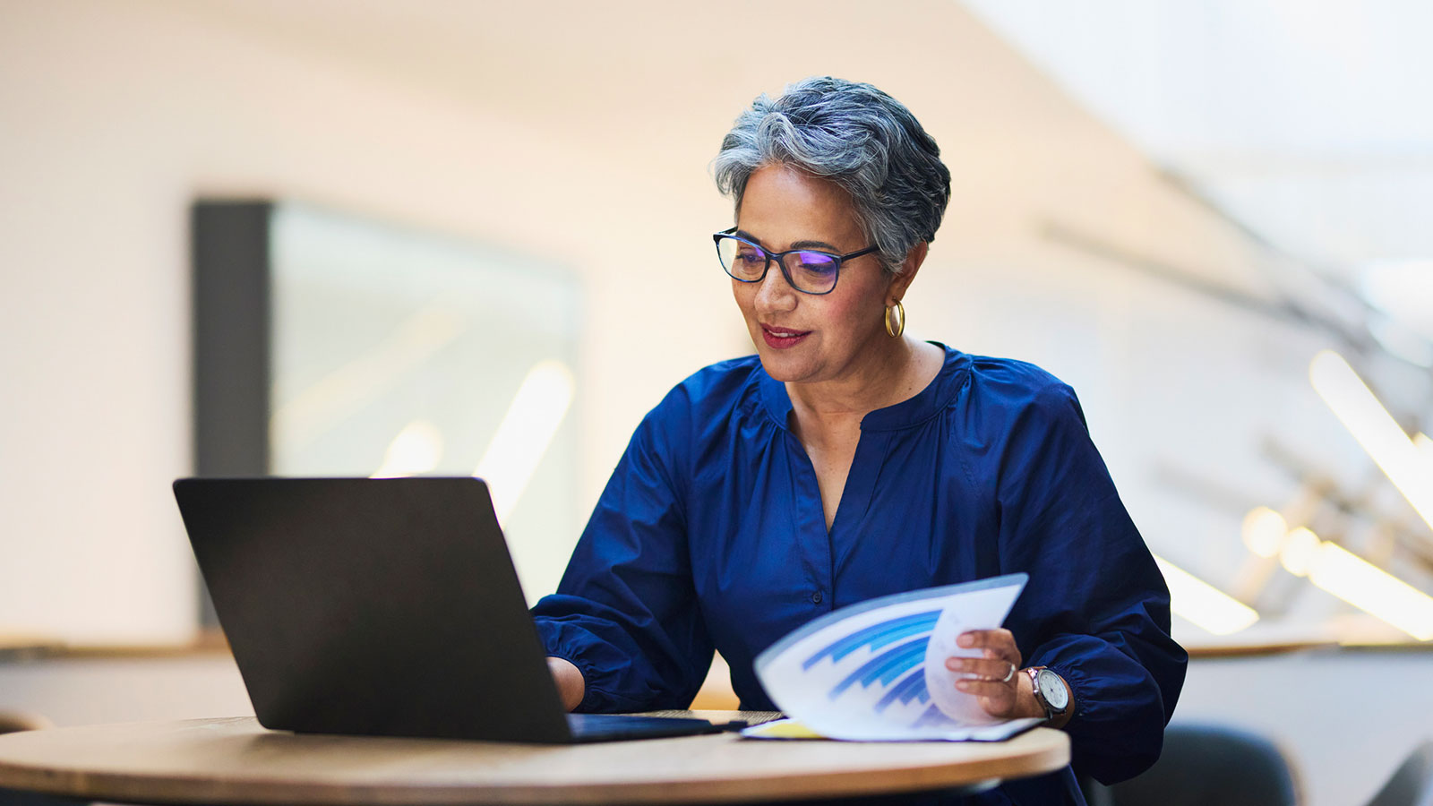 A woman in her late 50s reviews savings options on her laptop.