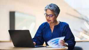A woman in her late 50s reviews savings options on her laptop.
