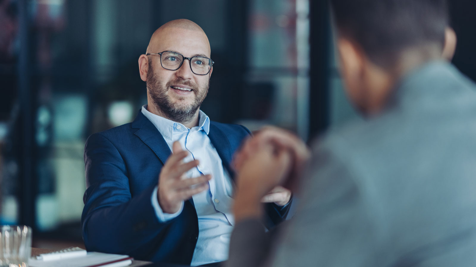 Man in glasses having meeting with another person at table.