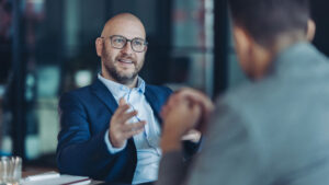 Man in glasses having meeting with another person at table.